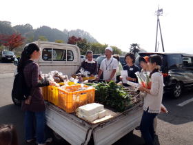 写真：トラックの荷台の野菜を囲むお母さんたち